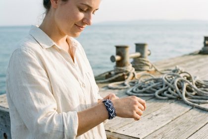 Jeune femme portant un bracelet marin en corde tressée sur un ponton en bois au bord de la mer