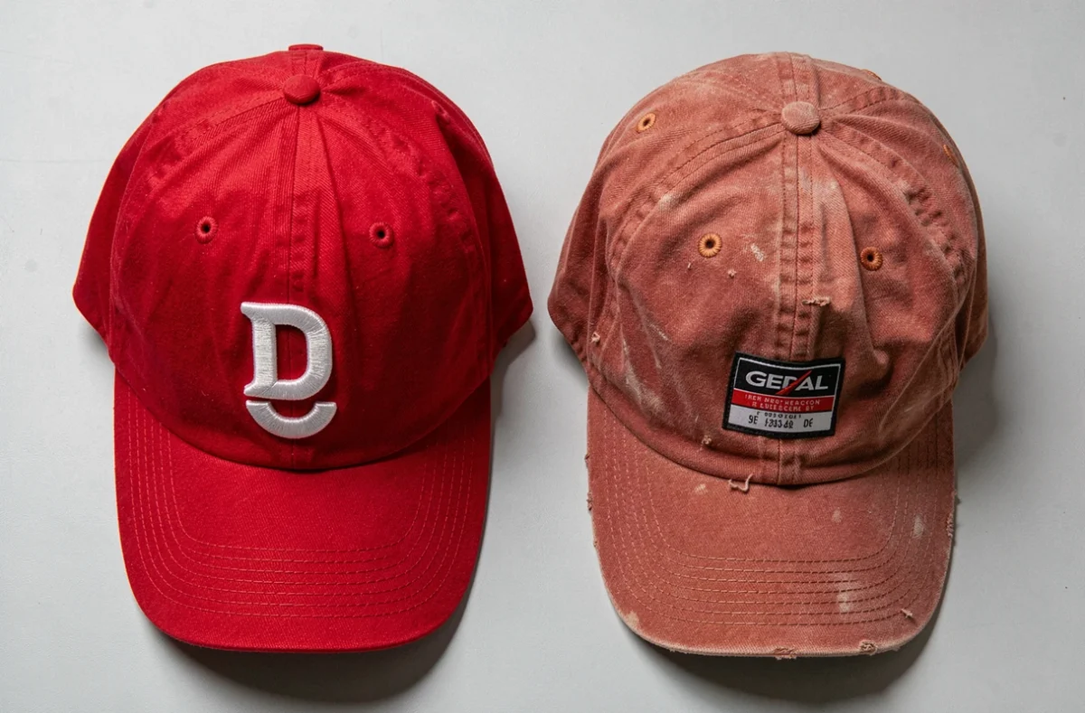 Comparaison de deux casquettes rouges, l'une authentique et l'autre contrefaite, posées côte à côte sur fond gris